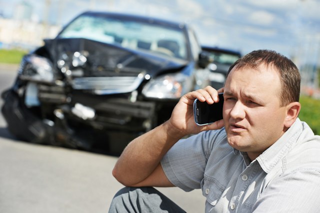 Accident de voiture : que faire ? Avant de voiture détruit - homme au téléphone